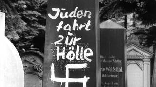Mit einem Hakenkreuz beschmierter Grabstein auf einem jüdischen Friedhof in Bamberg 1965. (Foto: dpa Bildfunk, Picture Alliance)