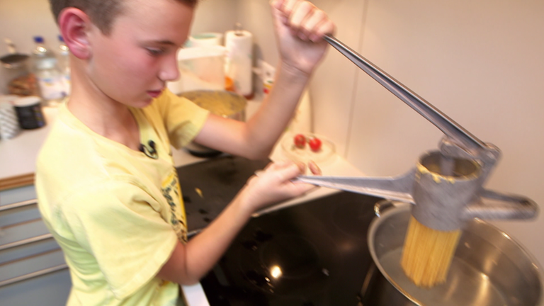 Thore drückt Käsespätzleteig durch eine Nudelpresse. (Foto: SWR)