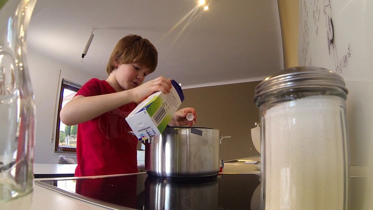 Nik schüttet Milch in einen Topf um Milchreis zu kochen. (Foto: SWR)