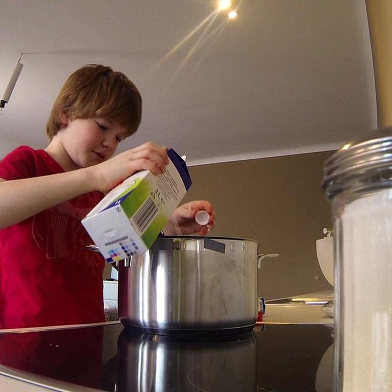 Nik schüttet Milch in einen Topf um Milchreis zu kochen. (Foto: SWR)