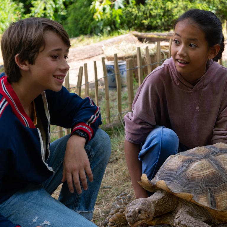 Ein Junge und ein Mädchen mit einer große Schildkröte im Garten (Foto: SWR, Maria Wiesler)