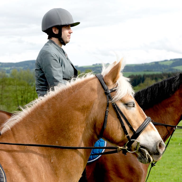 Zwei Reiter, ein junges Mädchen und ein Mann, sitzen auf ihren Pferden und schauen in die Landschaft. (Foto: SWR)