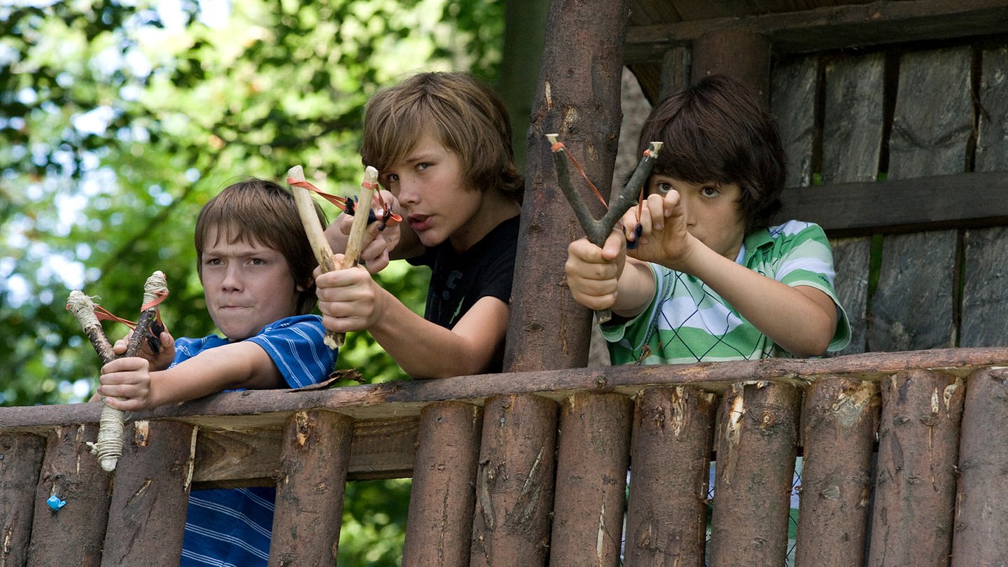 Drei Jungs stehen in ihrem Baumhaus und haben Steinschleudern gespannt zum Abschuss (Foto: SWR, SWR -)
