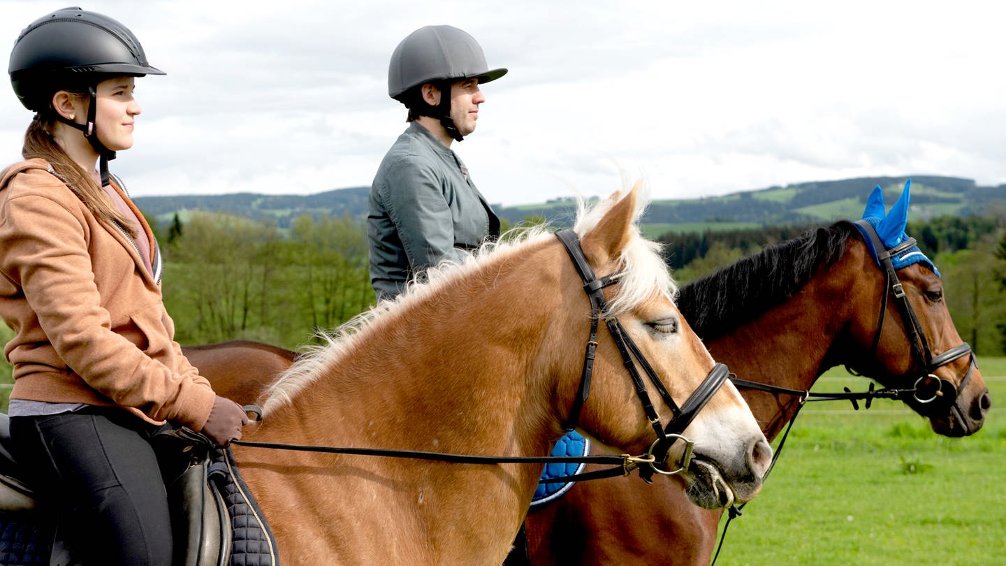 Zwei Reiter, ein junges Mädchen und ein Mann, sitzen auf ihren Pferden und schauen in die Landschaft. (Foto: SWR)