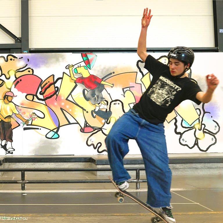 Skateboarder vor Graffiti-Leinwand