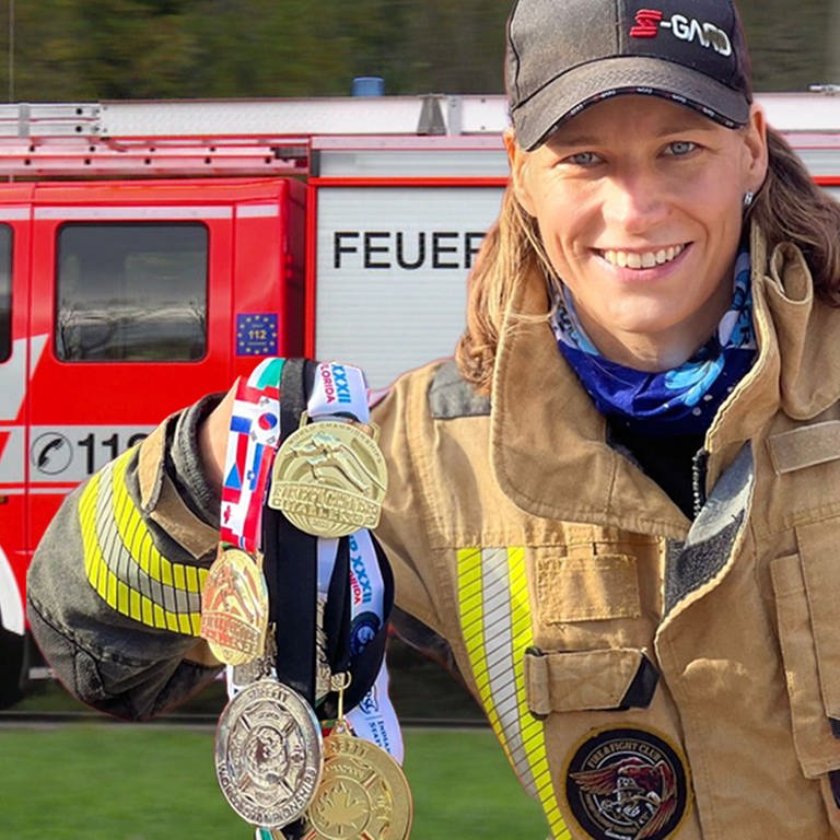 Feuerwehrfrau Marie Schuhmann mit Medaillen vor einem Feuerwehrauto