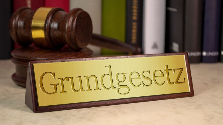 Grundgesetzschild und ein Hammer (Foto: Colourbox)