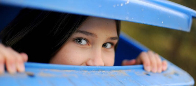 Mädchen schaut scherzhaft aus Mülltonne heraus (Foto: picture-alliance / Reportdienste, Frank May)