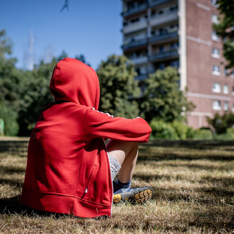 Ein Kind sitzt vor einem Plattenbau