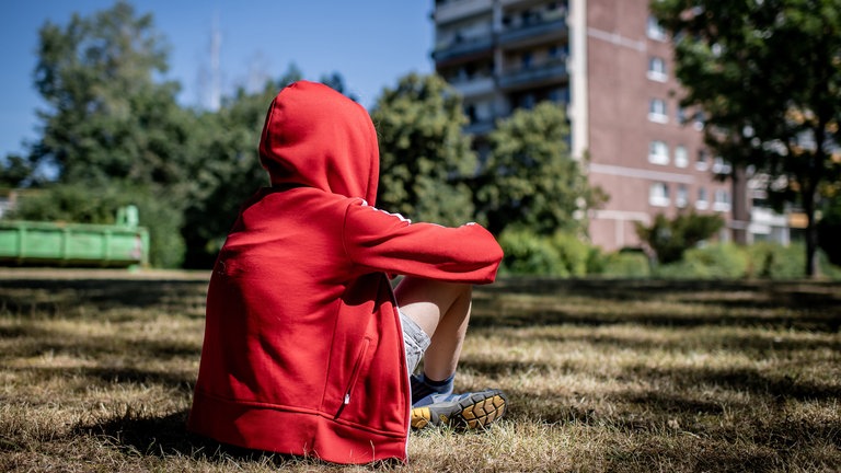 Ein Kind sitzt vor einem Plattenbau (Foto: picture-alliance / Reportdienste, Thomas Eisenhuth)