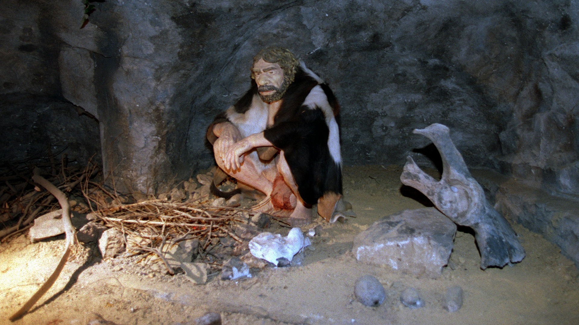 Eine Neanderthaler-Nachbildung in einer Höhle neben einer Feuerstelle (Foto: picture-alliance / Reportdienste, picture-alliance/ dpa/ Fotografen: Roland Scheidemann)