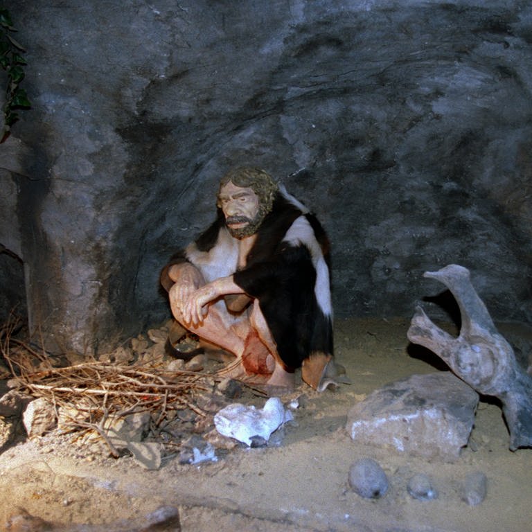 Eine Neanderthaler-Nachbildung in einer Höhle neben einer Feuerstelle (Foto: picture-alliance / Reportdienste, picture-alliance/ dpa/ Fotografen: Roland Scheidemann)