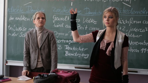 Linda steht vorne an der Tafel und meldet sich. (Foto: SWR, MDR)