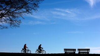 Zwei Radler fahren bei sonnigem und milden Winterwetter hinter einem blauen Himmel. (Foto: dpa Bildfunk, picture-alliance/ dpa/ Fotograf: Patrick Pleul) Zwei Radler fahren bei sonnigem und milden Winterwetter hinter einem blauen Himmel.
