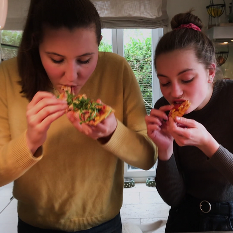Zwei Mädchen backen Pizza selbst.