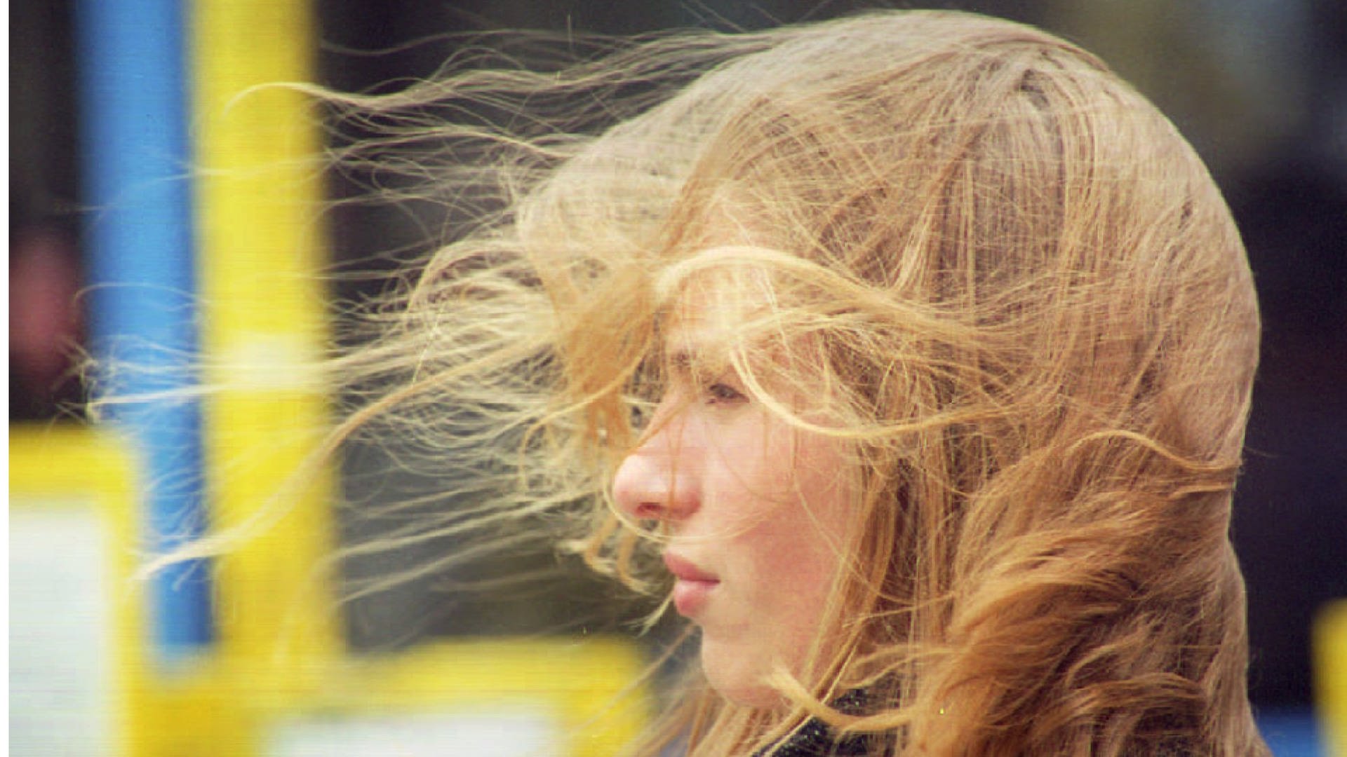 Eine Frau mit sturmzerzauster Frisur durch starken Wind. 